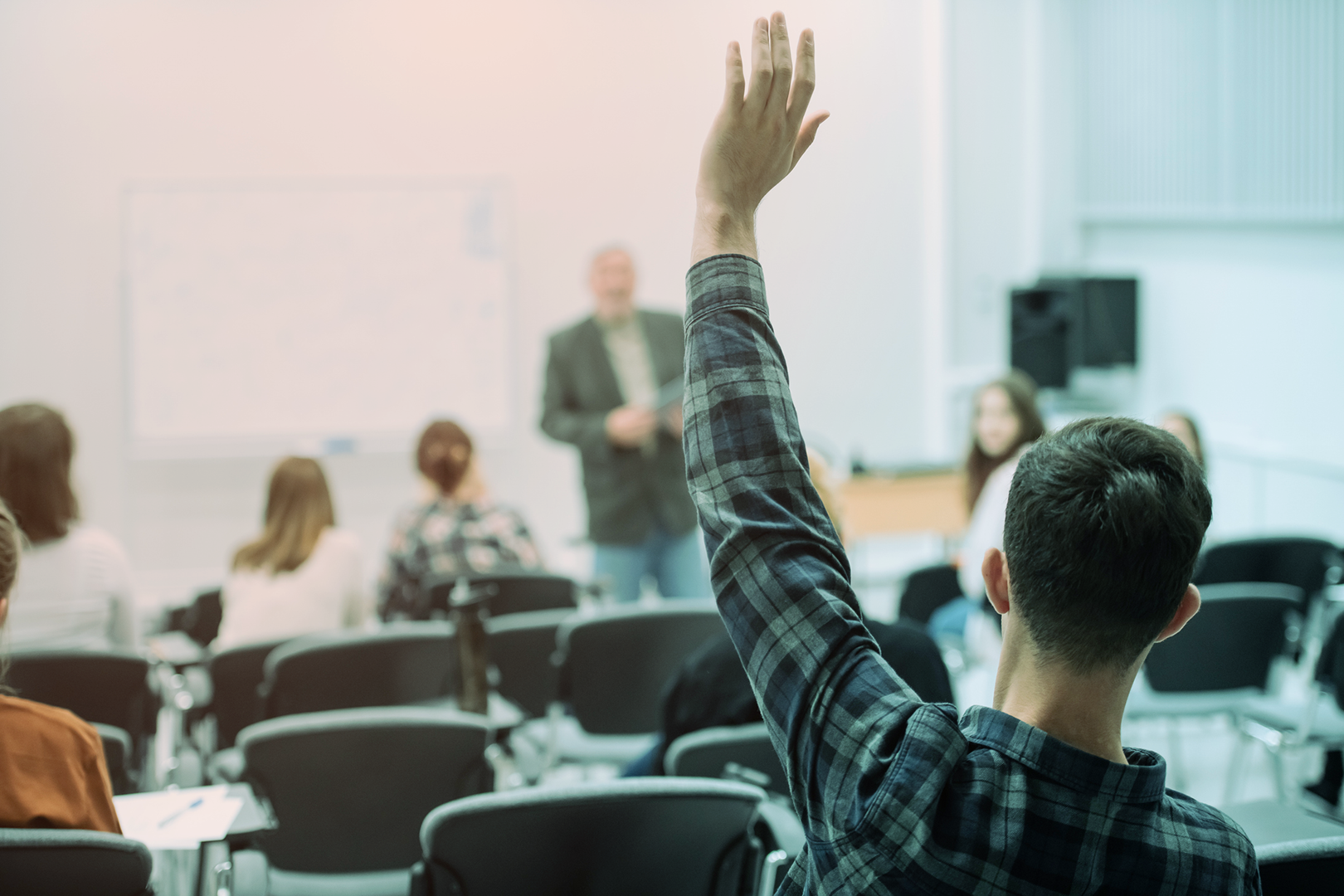 A student in a university lecture hall raising their hand (Stukent).